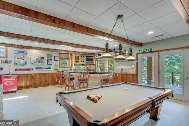 recreation room featuring bar area, a paneled ceiling, carpet floors, and wooden walls