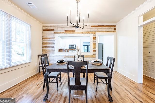 dining area featuring light hardwood / wood-style flooring, a chandelier, a healthy amount of sunlight, and crown molding