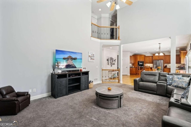 living room featuring light hardwood / wood-style floors, crown molding, a high ceiling, and ceiling fan