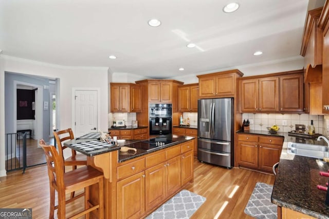 kitchen with black appliances, a center island, sink, and light hardwood / wood-style flooring