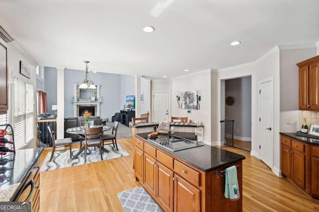 kitchen with light wood-type flooring, black electric stovetop, a kitchen island, decorative light fixtures, and crown molding