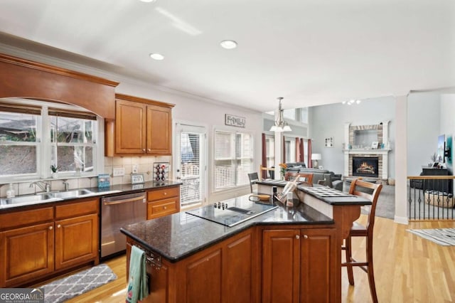 kitchen with stainless steel dishwasher, a kitchen island, light hardwood / wood-style flooring, and plenty of natural light