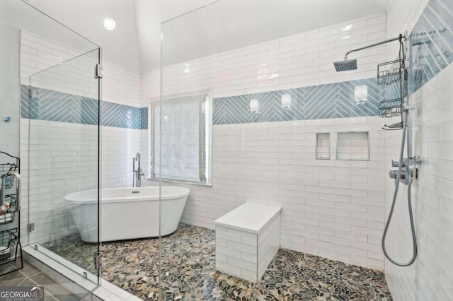 bathroom with shower with separate bathtub, tile patterned flooring, and tile walls