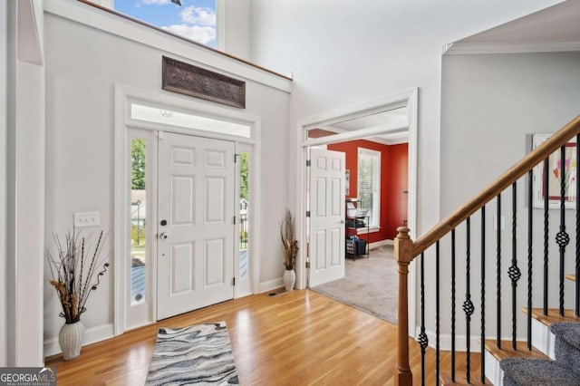 foyer entrance with wood-type flooring, crown molding, and a wealth of natural light