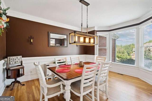 dining space with light hardwood / wood-style flooring and ornamental molding