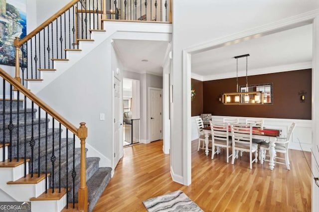 foyer entrance featuring a notable chandelier, light hardwood / wood-style flooring, and crown molding