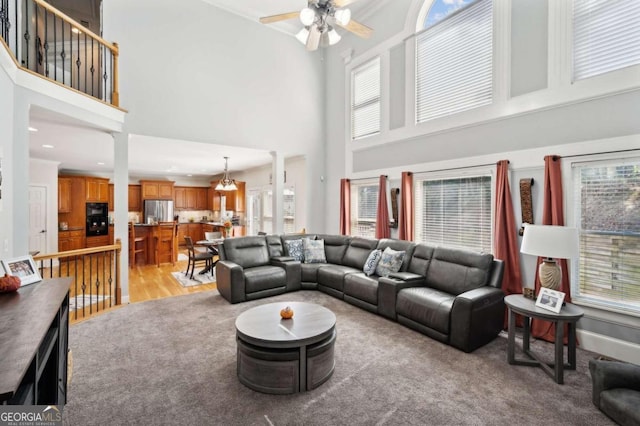 living room featuring ceiling fan, light wood-type flooring, and a high ceiling