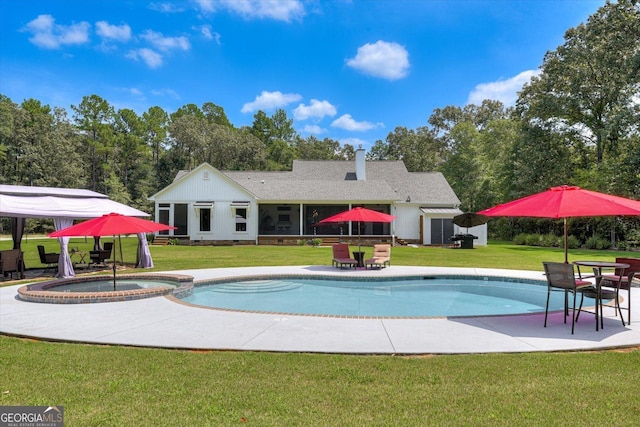1370 Deerwood Cir, Stapleton, GA 30823 - view of swimming pool featuring a lawn, a pool with connected hot tub, a sunroom, and a patio area