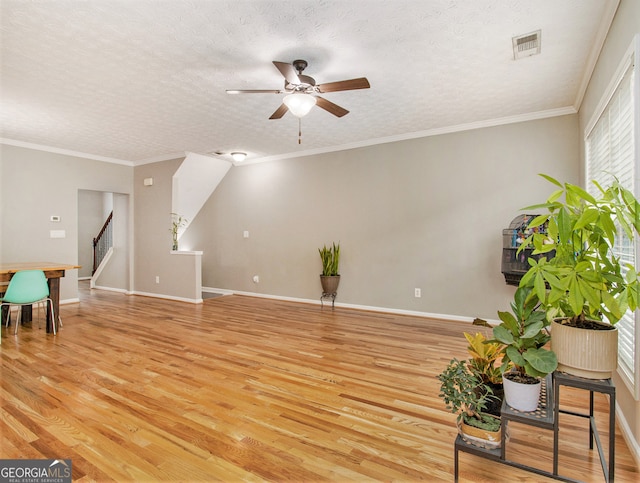 living area with a textured ceiling, crown molding, light hardwood / wood-style floors, and ceiling fan