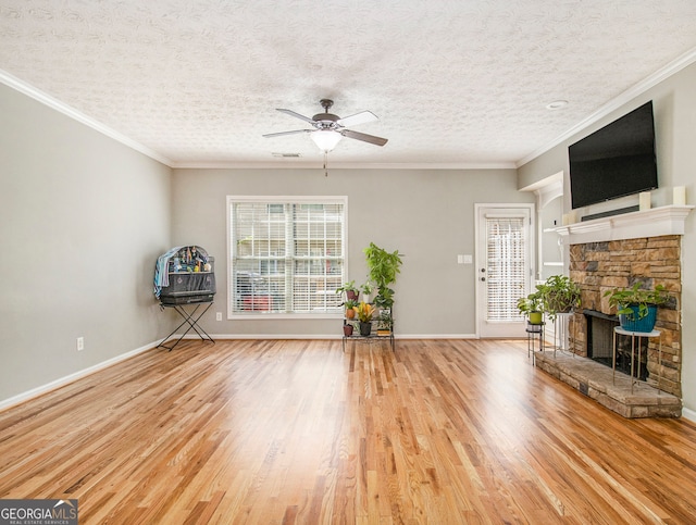 unfurnished living room featuring light wood-type flooring, ceiling fan, a fireplace, and a textured ceiling