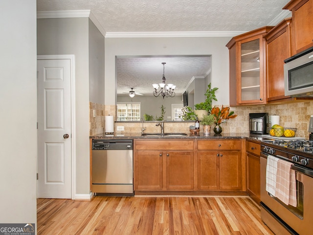 kitchen with hanging light fixtures, light hardwood / wood-style floors, stainless steel appliances, an inviting chandelier, and sink