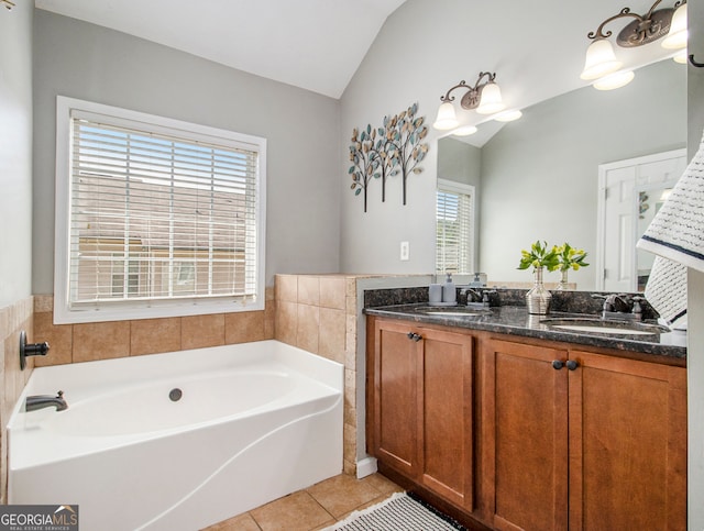 bathroom with vanity, a tub to relax in, vaulted ceiling, and tile patterned floors