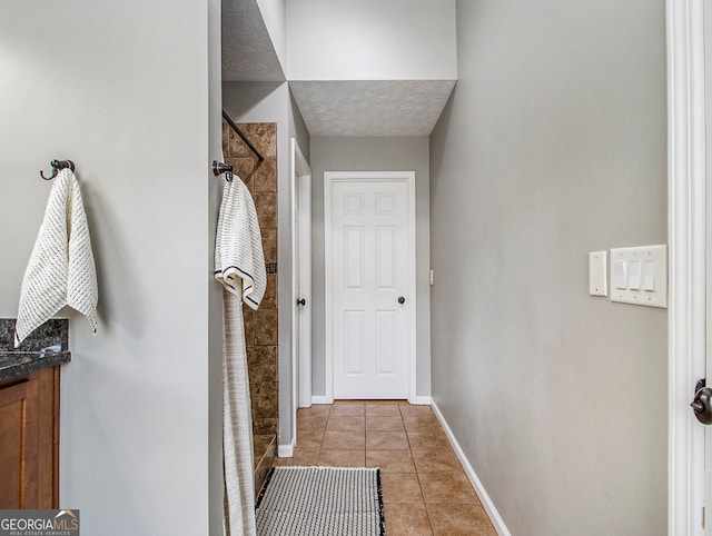 hall with a textured ceiling and light tile patterned floors