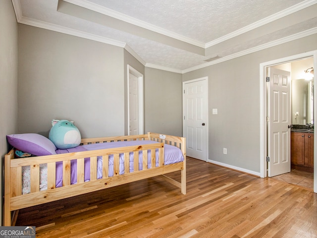 bedroom with light wood-type flooring, a textured ceiling, and crown molding