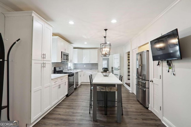 kitchen with white cabinets, appliances with stainless steel finishes, hanging light fixtures, and a kitchen island