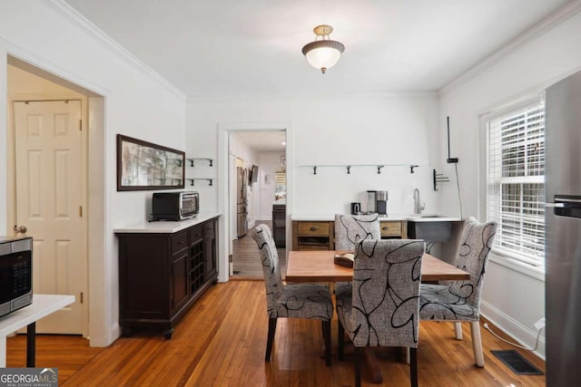 dining space with crown molding, light hardwood / wood-style floors, and sink