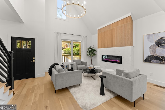 living room featuring a notable chandelier, light hardwood / wood-style floors, and high vaulted ceiling