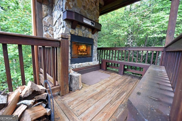 wooden terrace featuring an outdoor stone fireplace