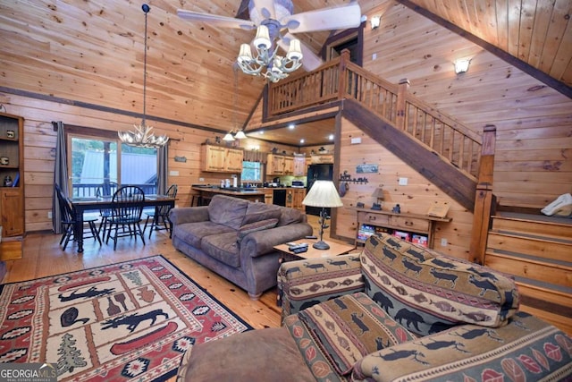 living room with wood ceiling, light hardwood / wood-style floors, ceiling fan with notable chandelier, high vaulted ceiling, and wooden walls