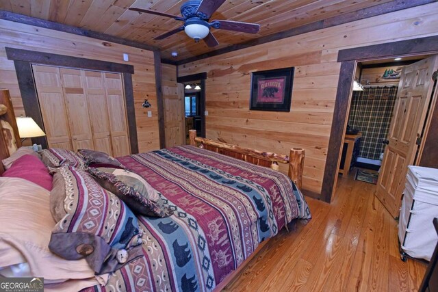 bedroom featuring wood ceiling, a closet, ceiling fan, light hardwood / wood-style flooring, and wooden walls