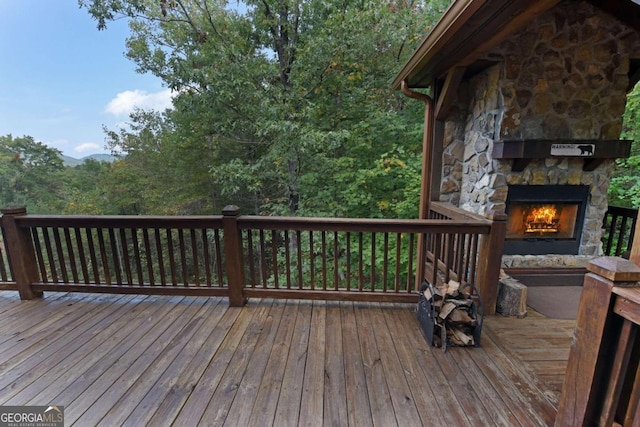 wooden terrace featuring an outdoor stone fireplace