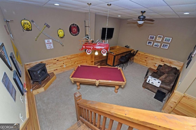 game room with a wood stove, carpet flooring, a drop ceiling, ceiling fan, and pool table