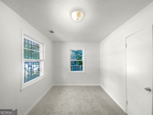 carpeted empty room with a textured ceiling