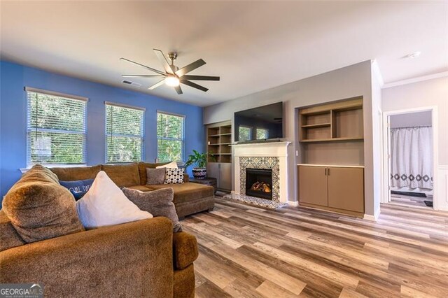 living room with light hardwood / wood-style floors, ornamental molding, ceiling fan, and plenty of natural light