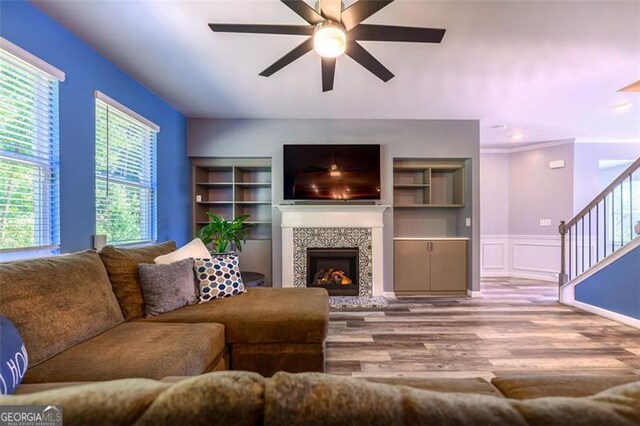 living room with ceiling fan, light hardwood / wood-style flooring, a fireplace, and ornamental molding