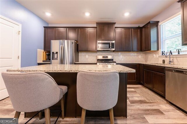 kitchen with light stone countertops, light hardwood / wood-style floors, a center island, and stainless steel appliances