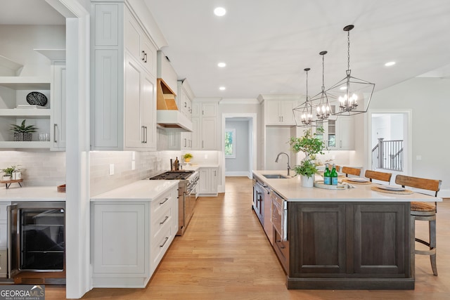 kitchen with an island with sink, beverage cooler, a kitchen breakfast bar, and custom exhaust hood