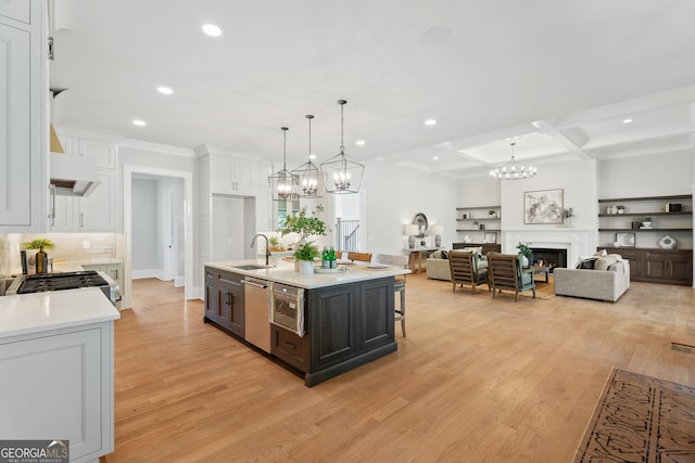 kitchen featuring pendant lighting, white cabinets, light hardwood / wood-style flooring, and a kitchen island with sink