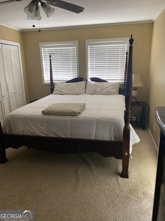 carpeted bedroom featuring ceiling fan, ornamental molding, and a closet