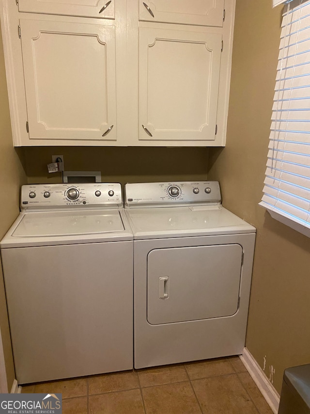 laundry area with a wealth of natural light, cabinets, separate washer and dryer, and light tile patterned floors