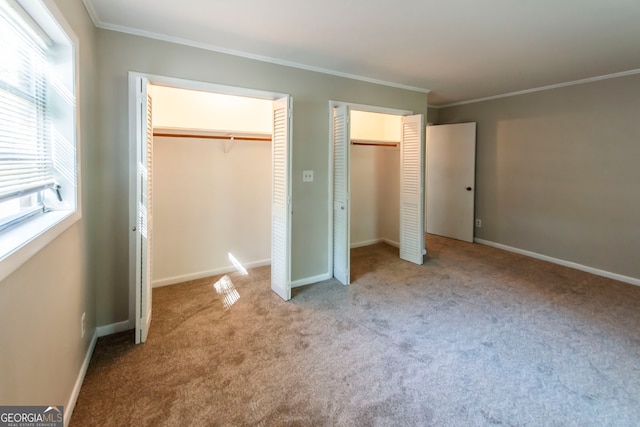 unfurnished bedroom with crown molding, light carpet, and multiple closets