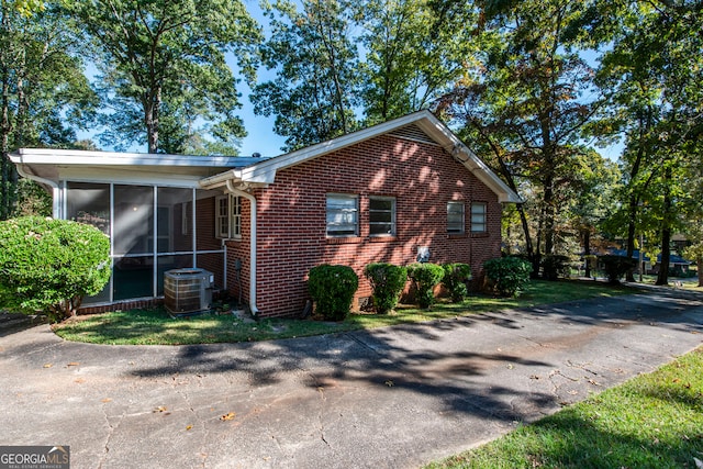 view of side of property featuring central AC unit and a sunroom