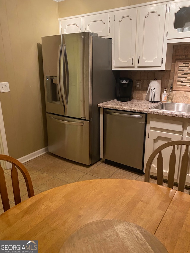 kitchen featuring sink, light tile patterned flooring, decorative backsplash, white cabinets, and appliances with stainless steel finishes