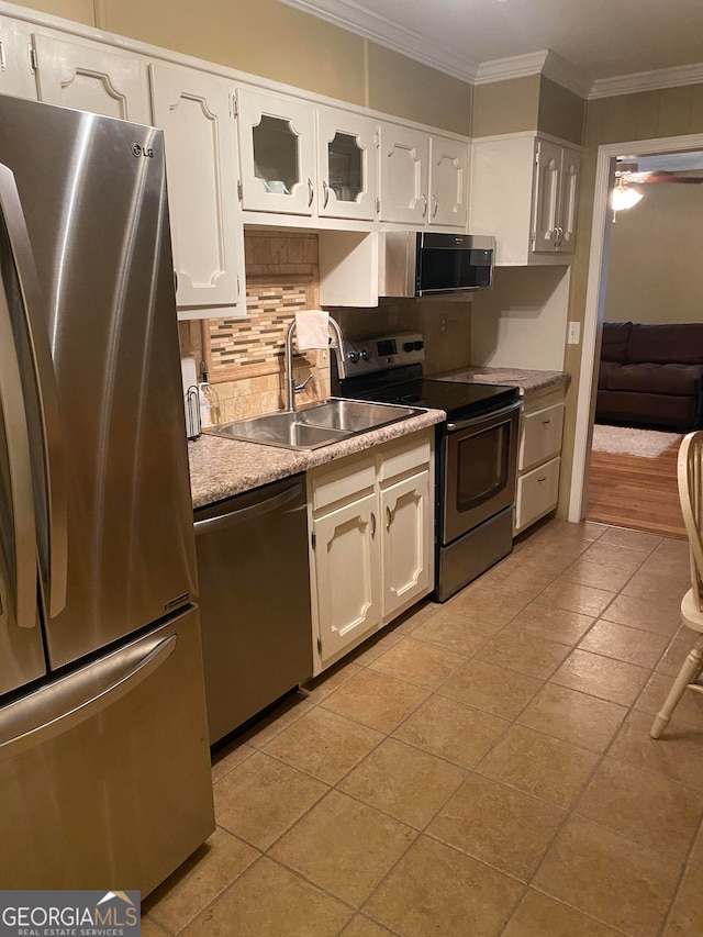 kitchen with white cabinetry, sink, backsplash, appliances with stainless steel finishes, and ornamental molding