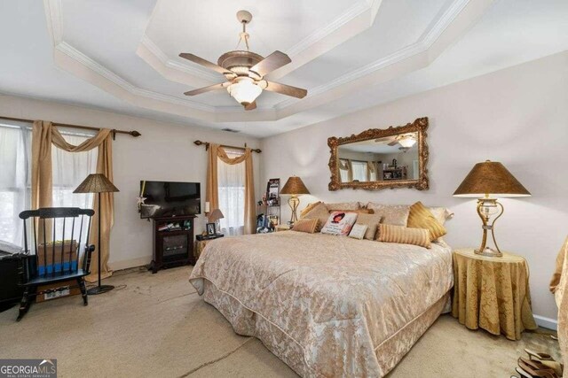 bedroom featuring ornamental molding, a tray ceiling, ceiling fan, and light colored carpet