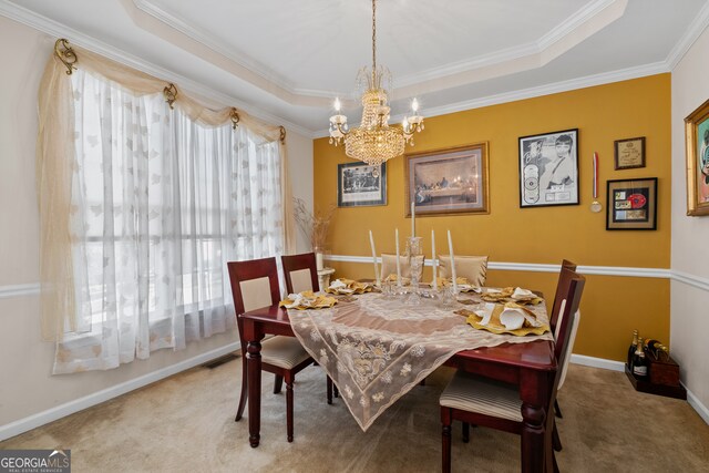 carpeted dining space featuring a chandelier, a raised ceiling, and ornamental molding