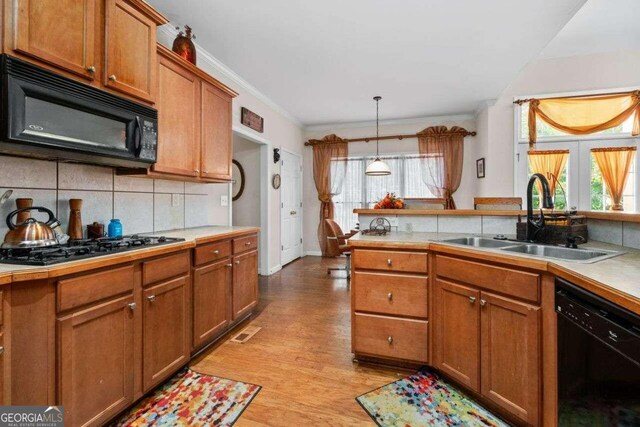 kitchen featuring black appliances, crown molding, sink, light hardwood / wood-style flooring, and decorative light fixtures