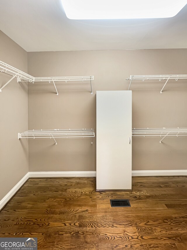 walk in closet with dark wood-type flooring