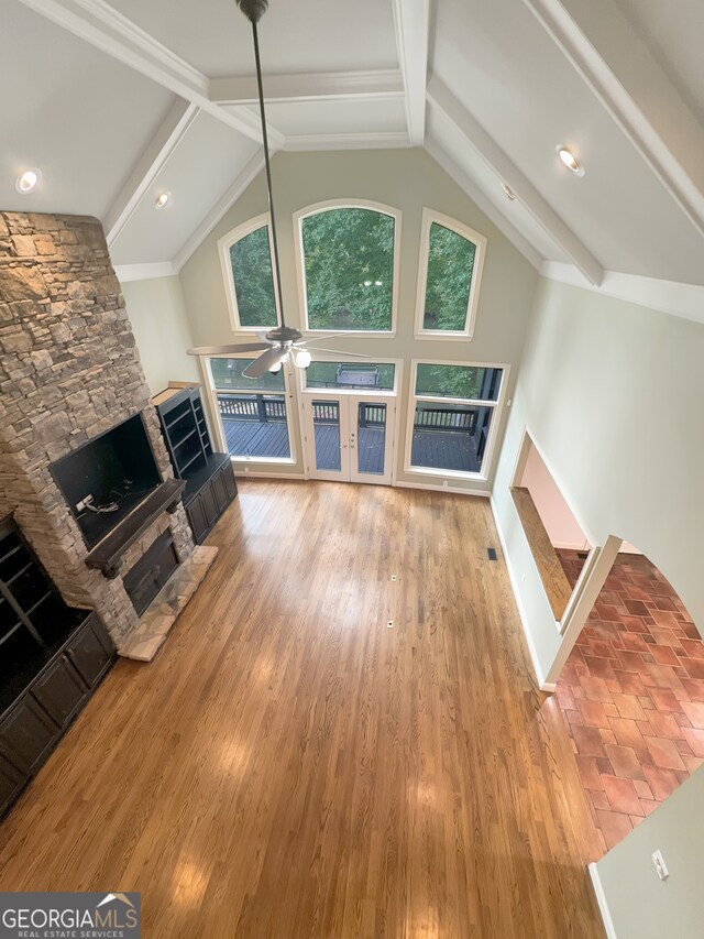 unfurnished living room featuring high vaulted ceiling, a stone fireplace, wood-type flooring, beam ceiling, and ceiling fan