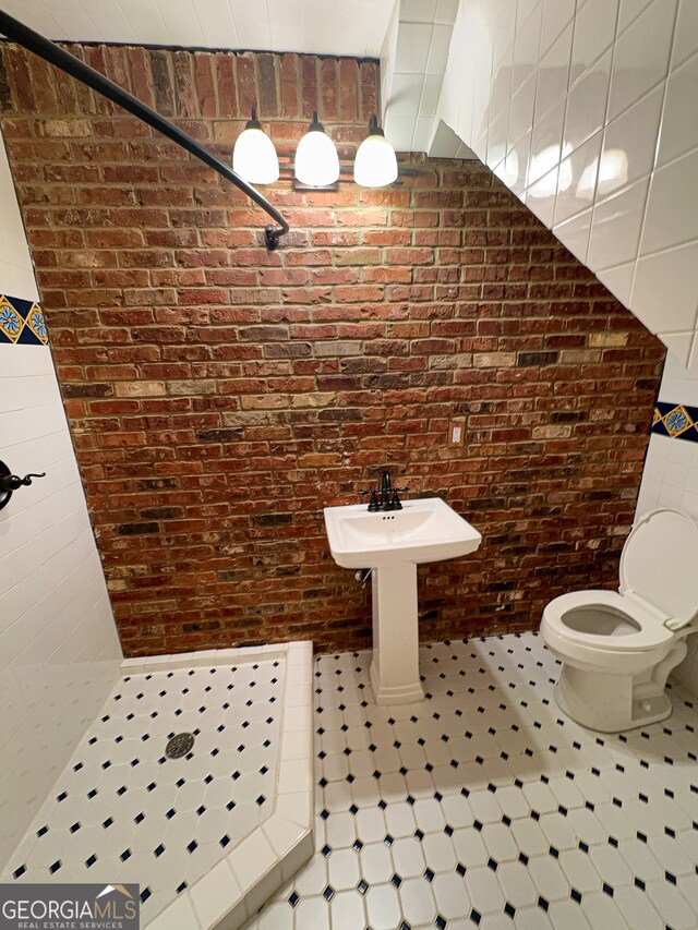 bathroom featuring brick wall, a shower, and toilet