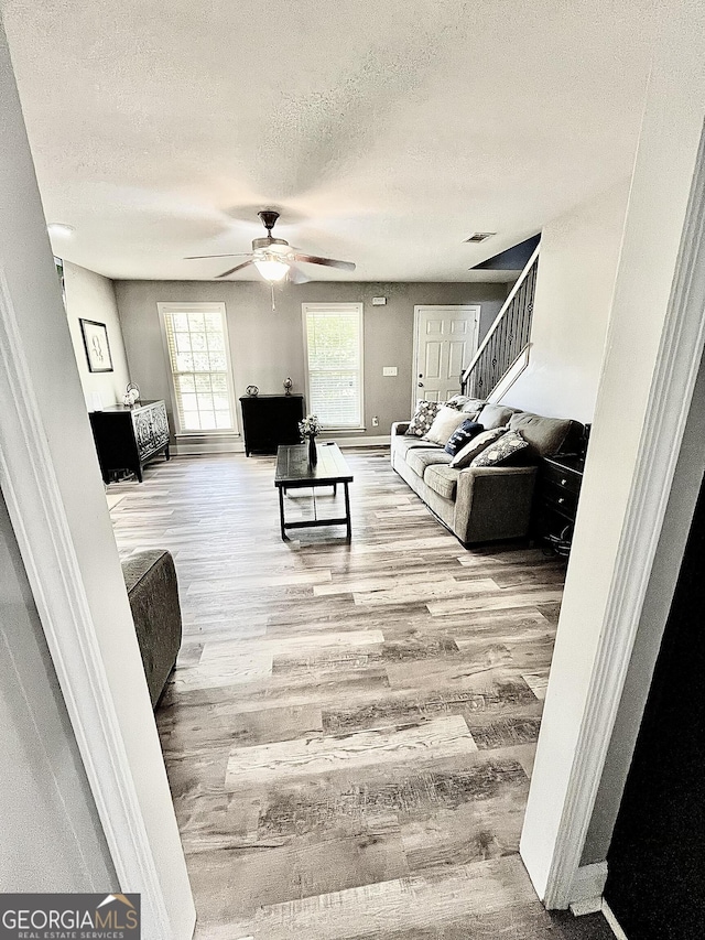 living room featuring hardwood / wood-style floors, a textured ceiling, and ceiling fan