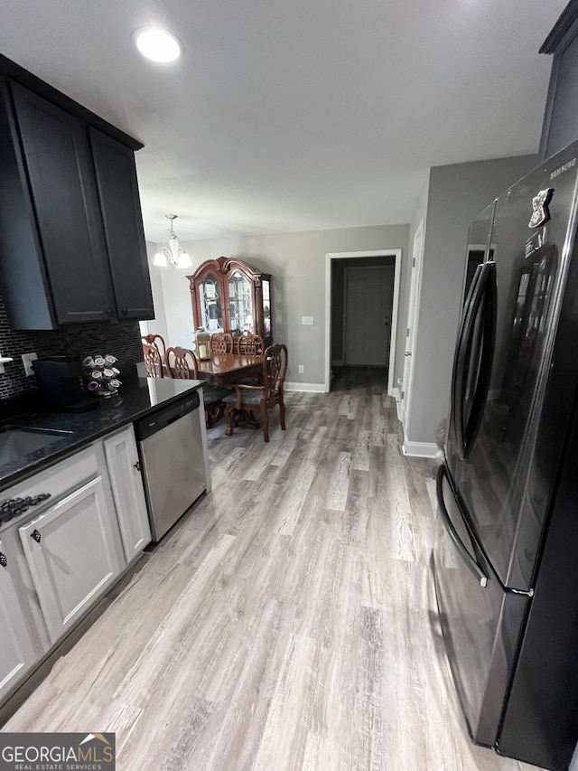 kitchen with tasteful backsplash, stainless steel dishwasher, fridge, an inviting chandelier, and light hardwood / wood-style floors