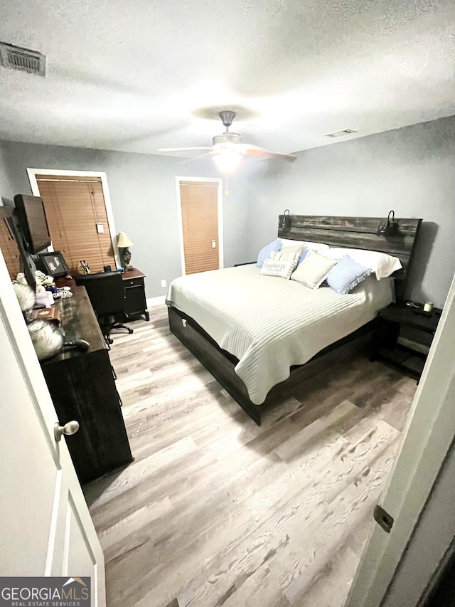 bedroom with wood-type flooring, a textured ceiling, and ceiling fan