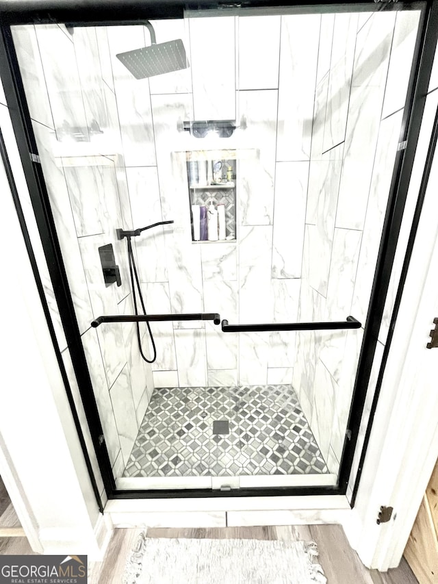 bathroom with a shower with door and hardwood / wood-style flooring