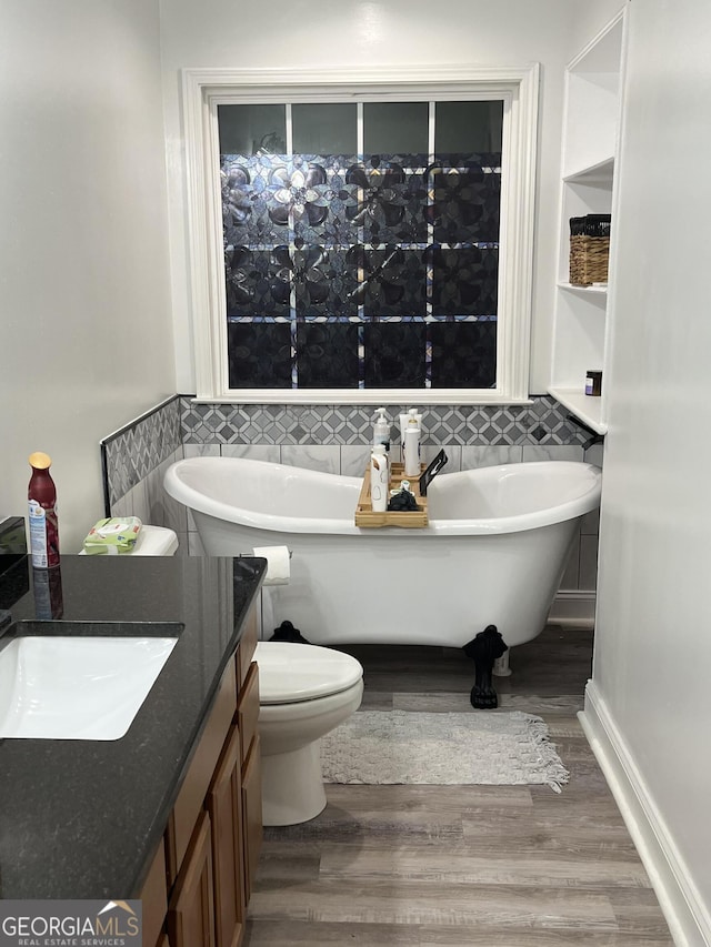 bathroom with hardwood / wood-style flooring, a tub, toilet, and vanity