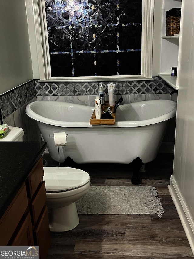 bathroom featuring a bath, hardwood / wood-style flooring, vanity, and toilet